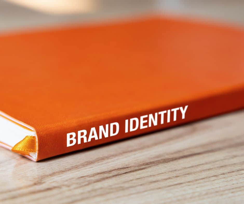 book with orange cover titled 'BRAND IDENTITY' laying on a wooden surface