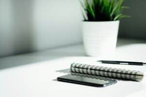 pen, notebook, and smartphone on white table